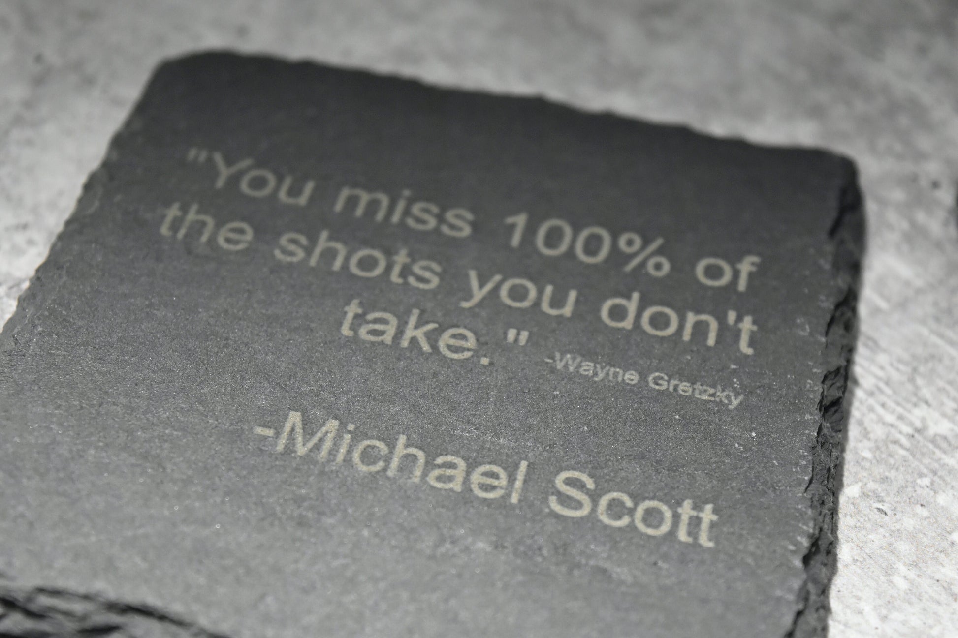 Motivational quote on a slate stone with a blurred background. wayne gretzky. michael scott